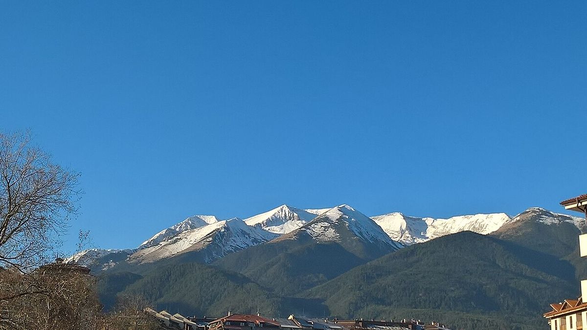 The town of Bansko in southwest Bulgaria, with red-tiled roofs and the Pirin mountains rising sharply behind, snow-capped in winter